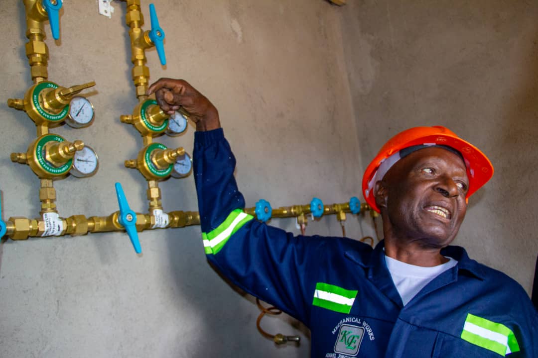Kinmel technician in an orange hard hat and blue reflective workwear checking medical gas regulators.